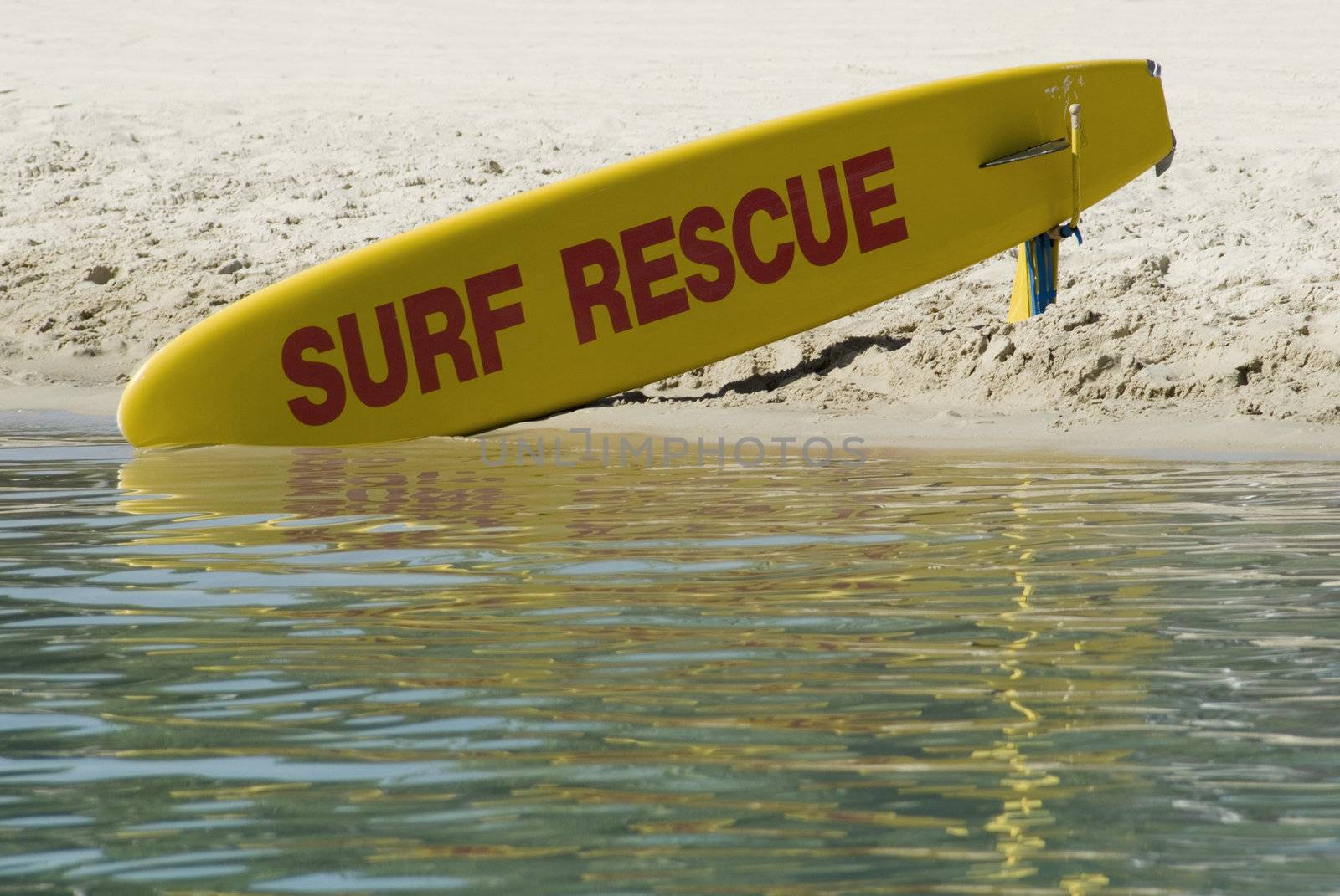 A bright yellow surfboard, standing by for use by surf rescue