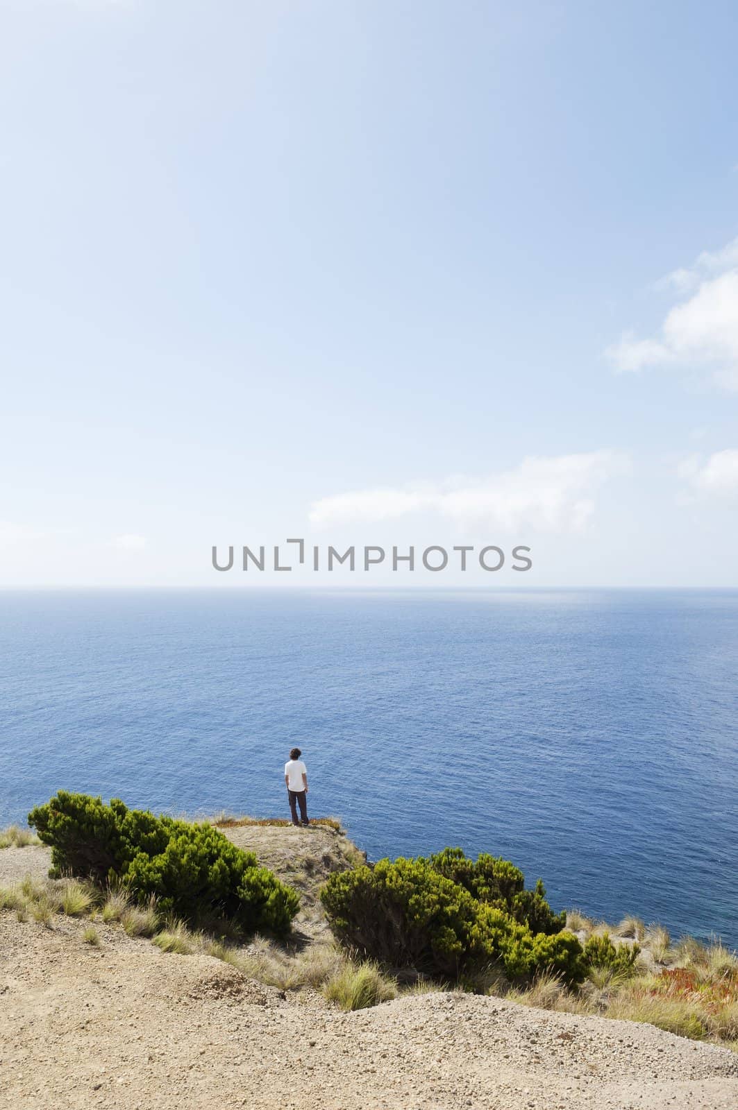 Man at the edge of a cliff  looking at sea in Faial island, Azores, Portugal