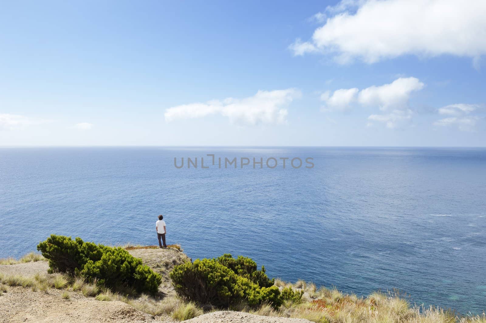 Man at the edge of a cliff  looking at sea in Faial island, Azores, Portugal