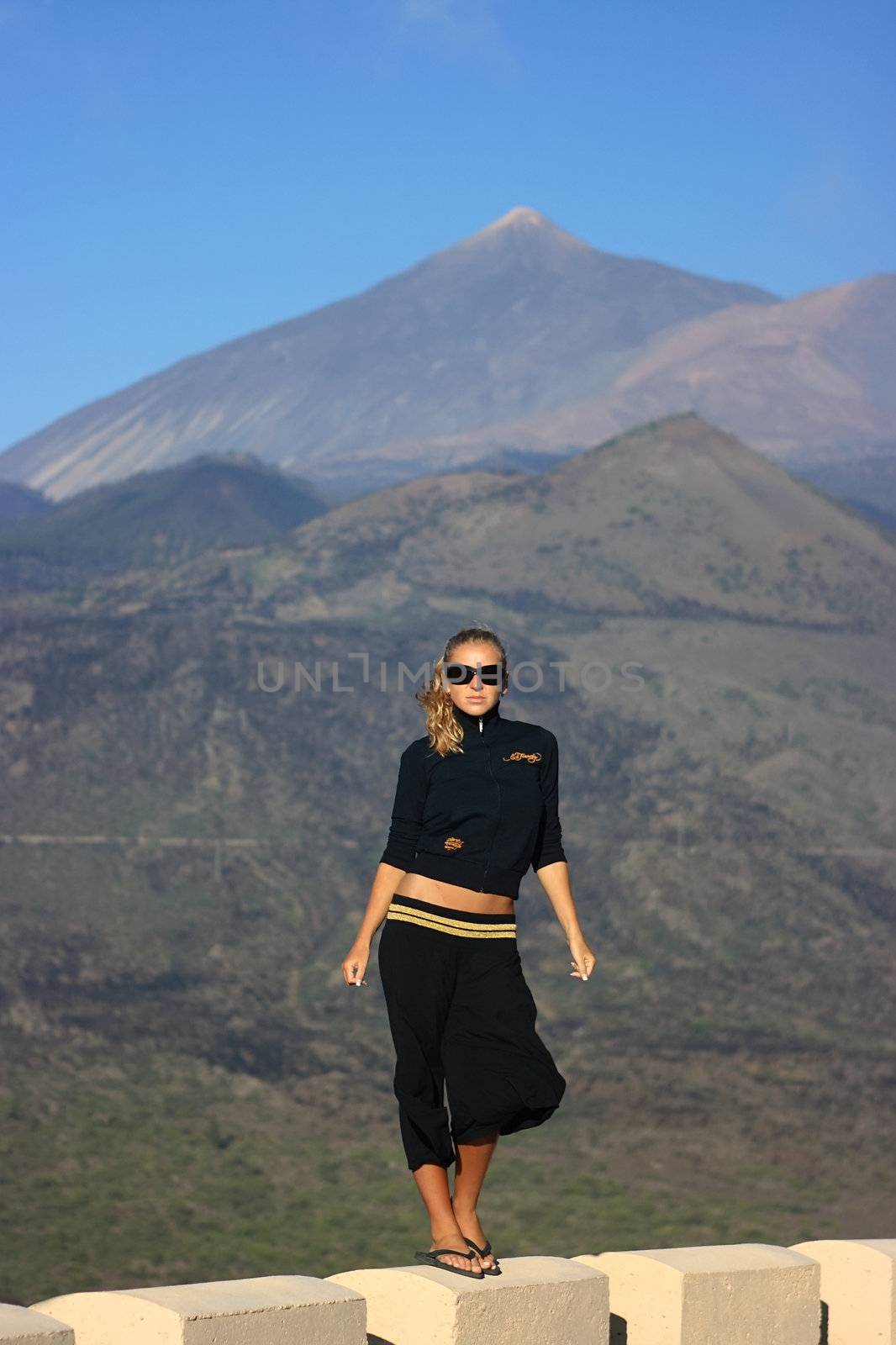 Yound lady in sunglasses and volcano on the background