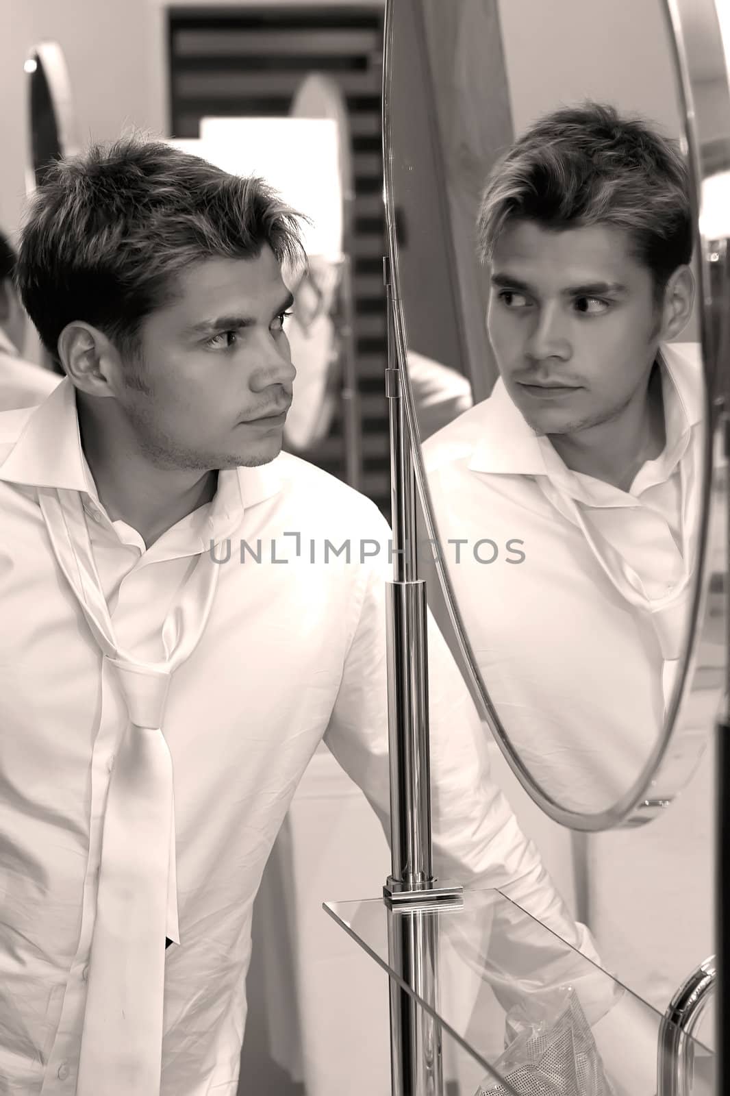 Young handsome man looking at himself in the mirror