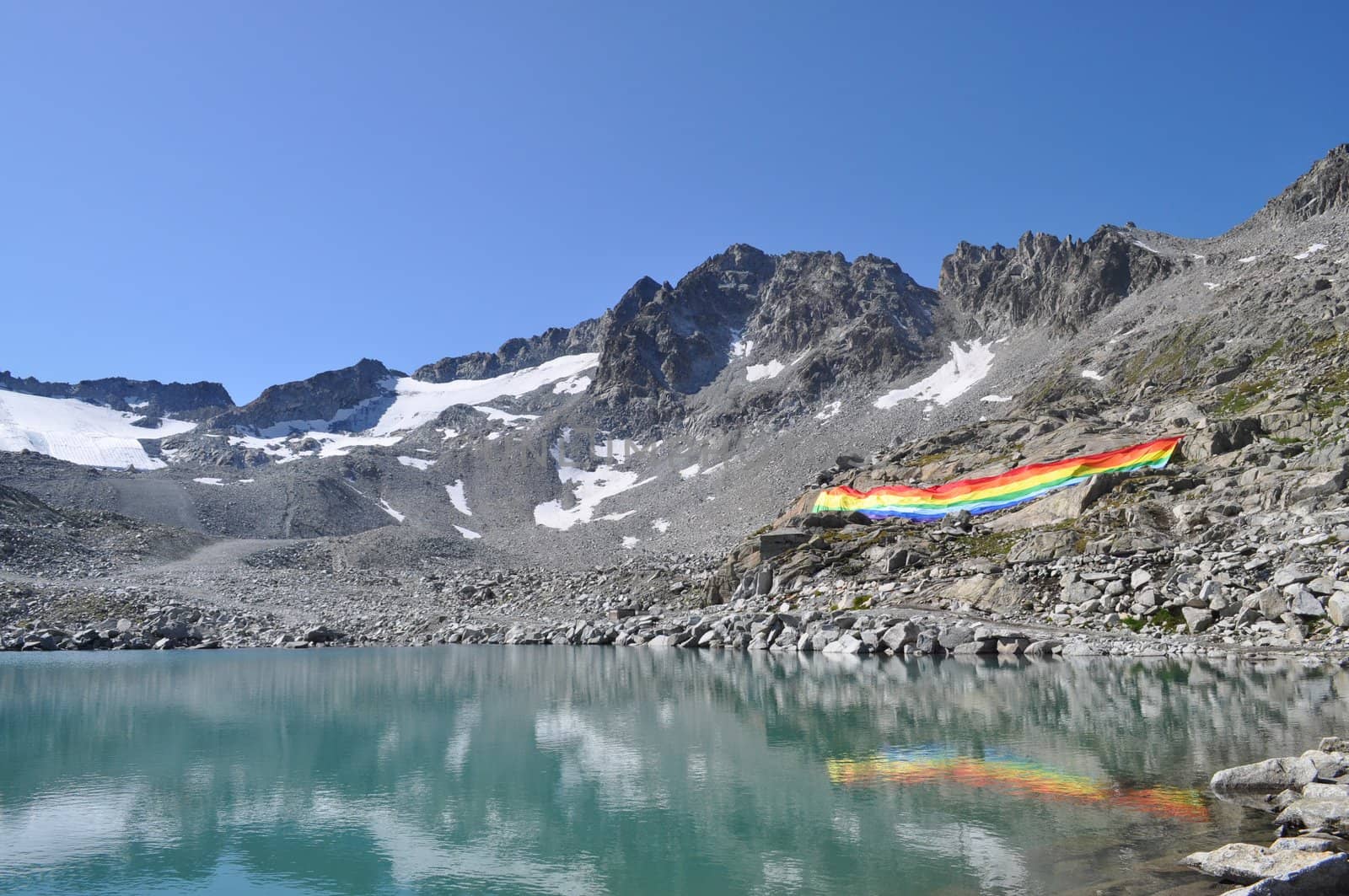 Peace flag dropped in mountain reflected in a lake, Adamello Italy