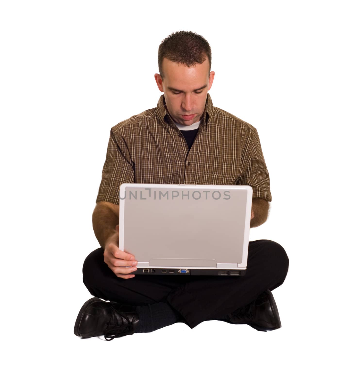 A young man sitting cross legged on the floor with a laptop