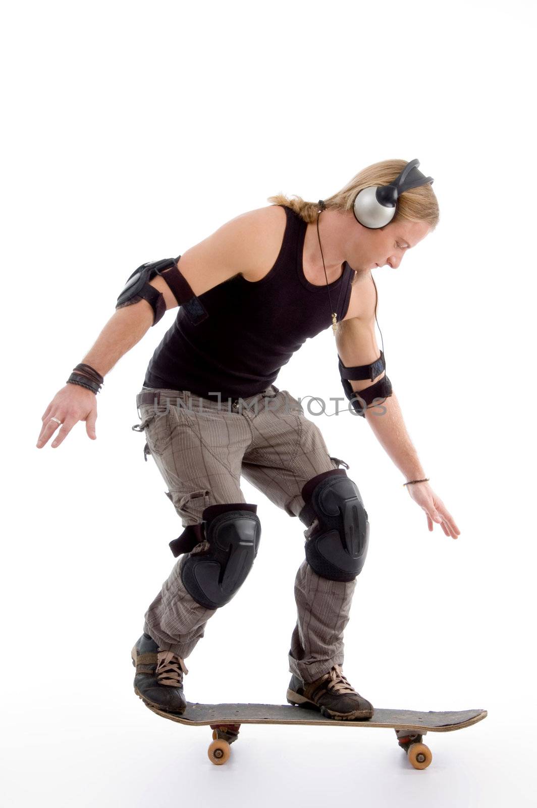 young male model balancing skateboard against white background