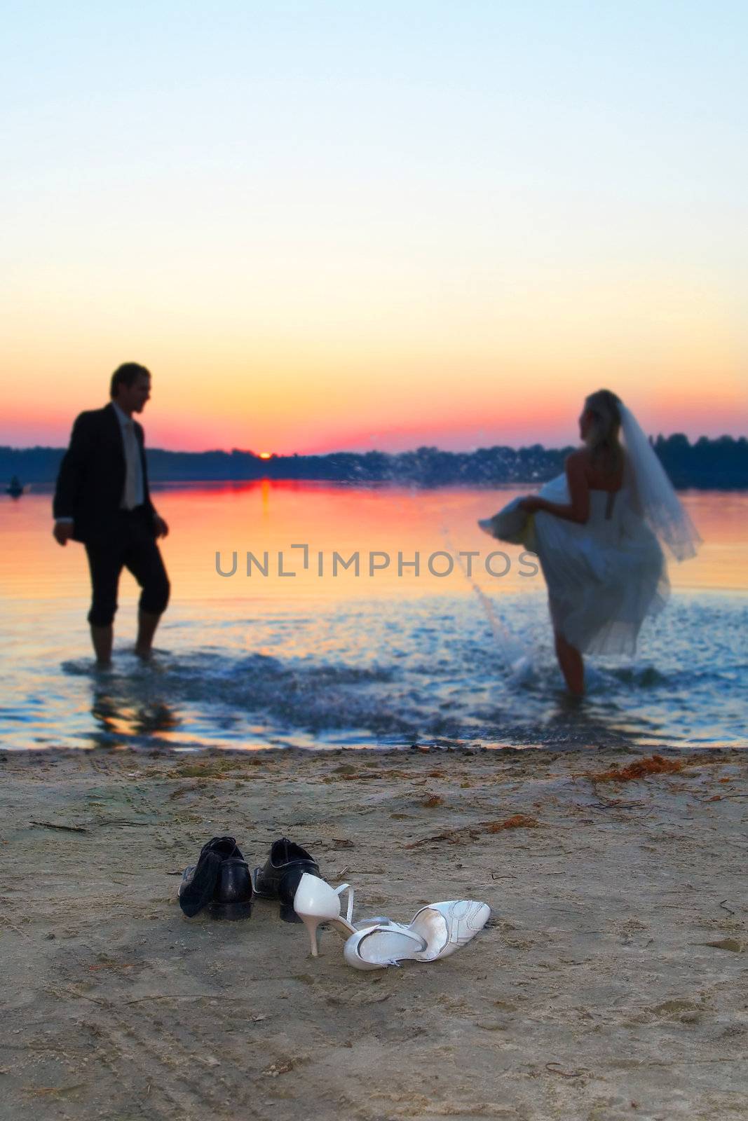 the young couple is standing after the marriage ceremony on the beach and cuddling