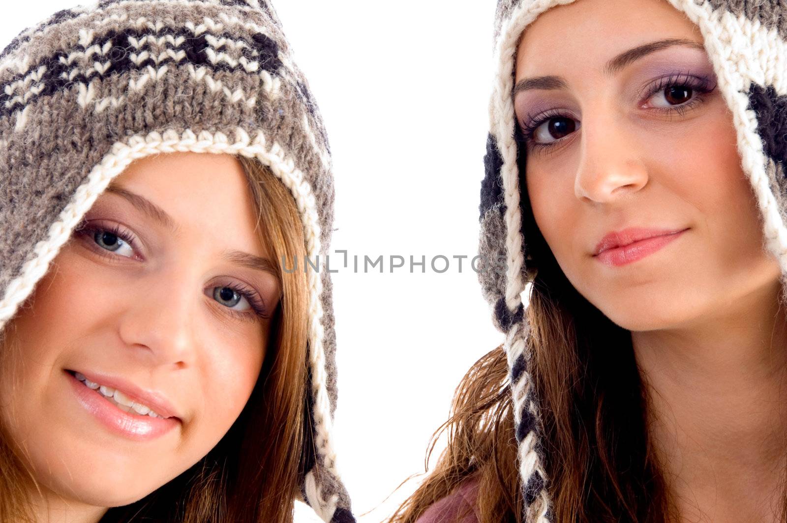 two young friends wearing woolen cap and looking at camera on an isolated white background