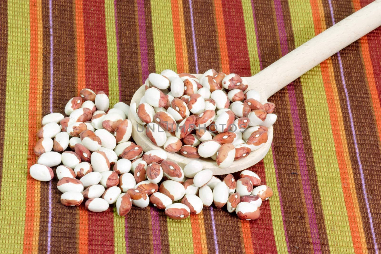 Red and white beans on a cooking spoon as background