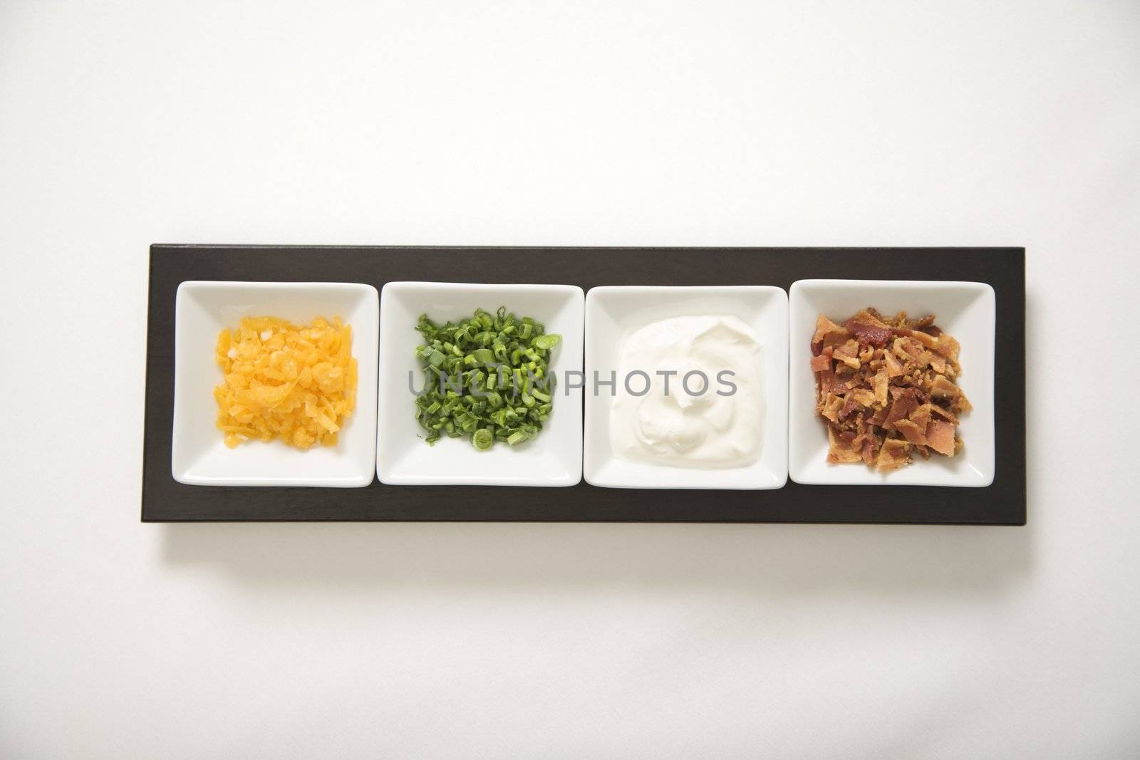 Baked potato side dishes filled with cheese, scallion onions, sour cream, and bacon.