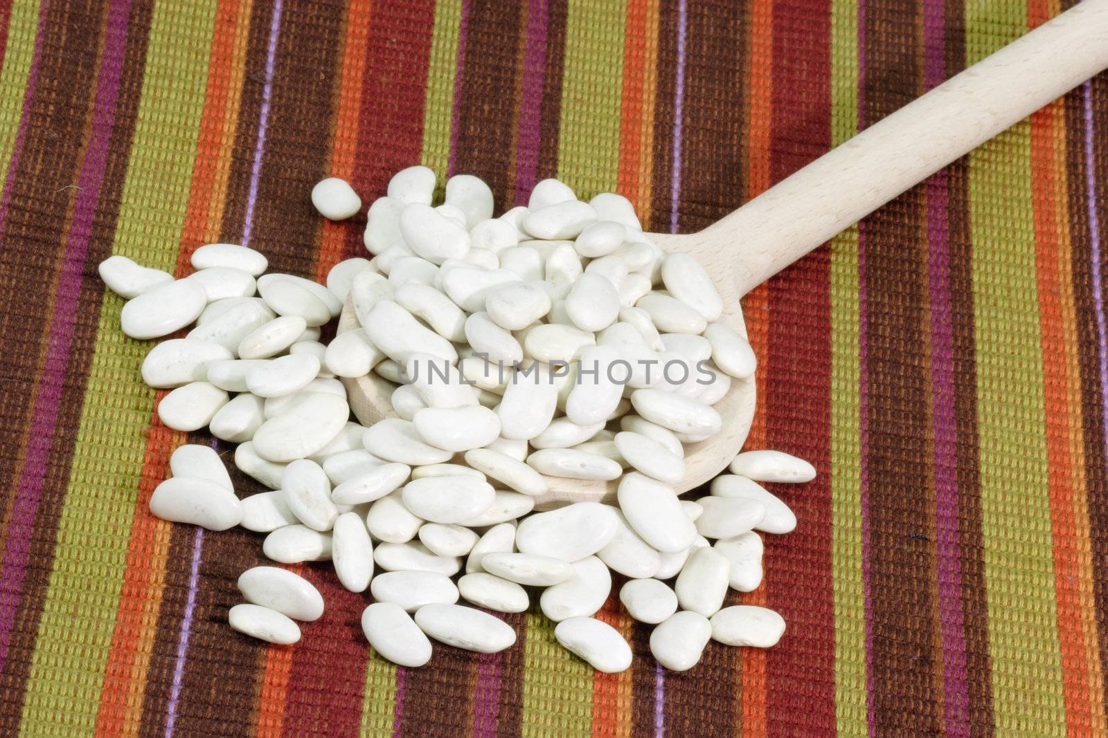 White beans on a cooking spoon as background