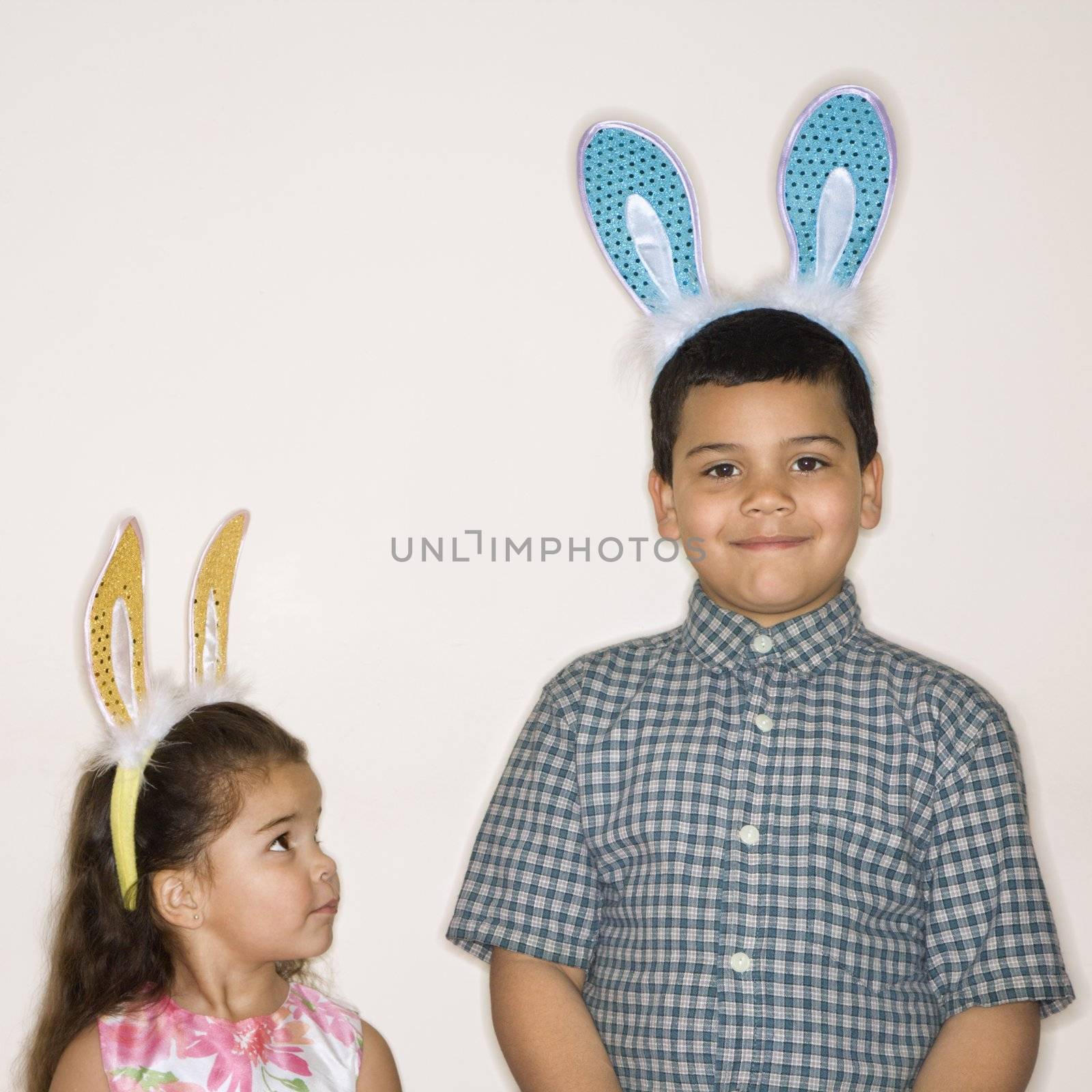 Hispanic girl looking up at Hispanic boy both wearing bunny ears.