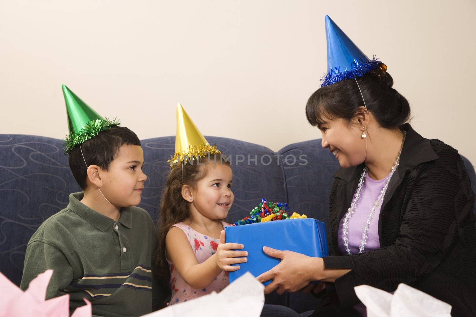 Mother giving present to daughter at birthday party.