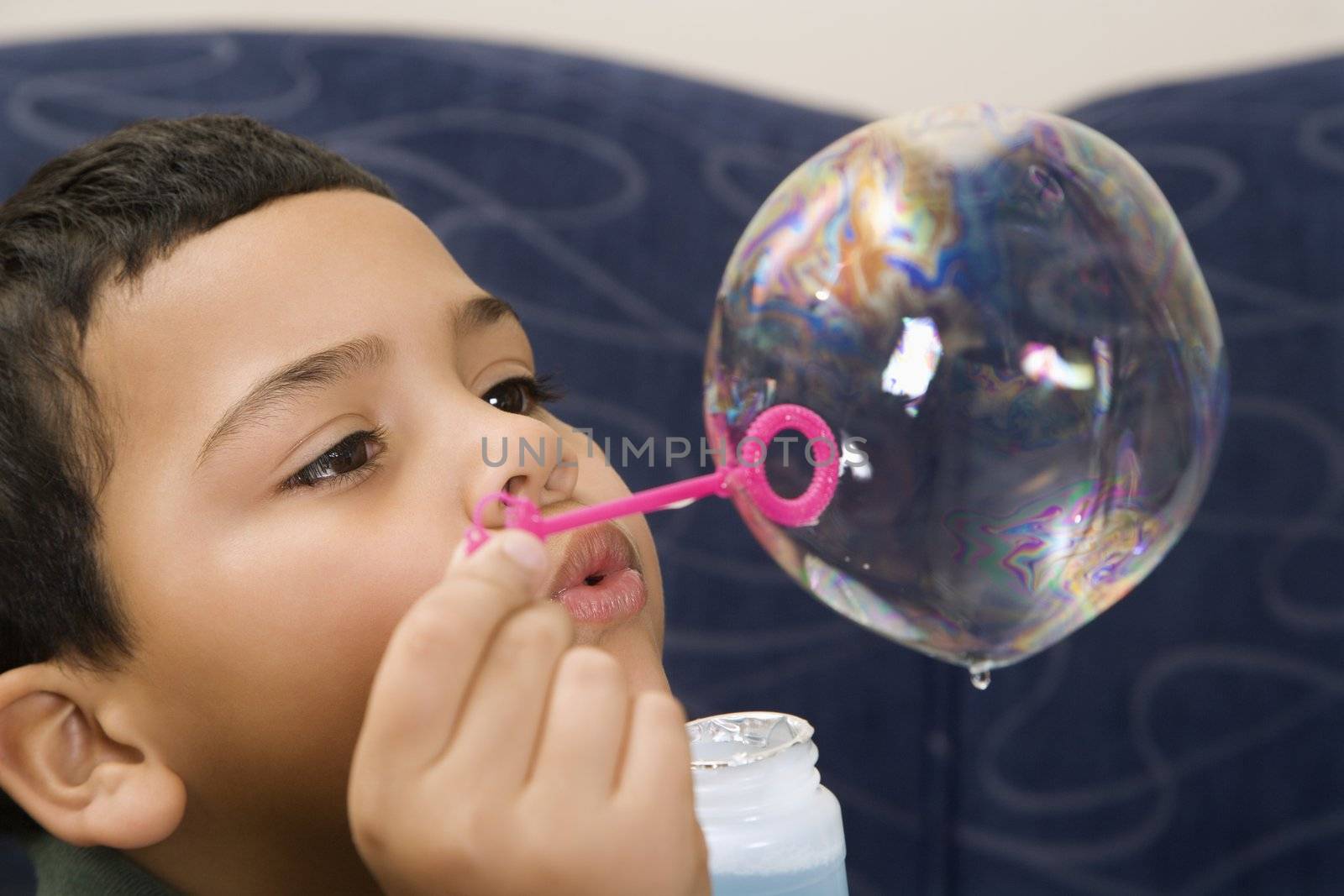 Hispanic boy blowing large soap bubble.