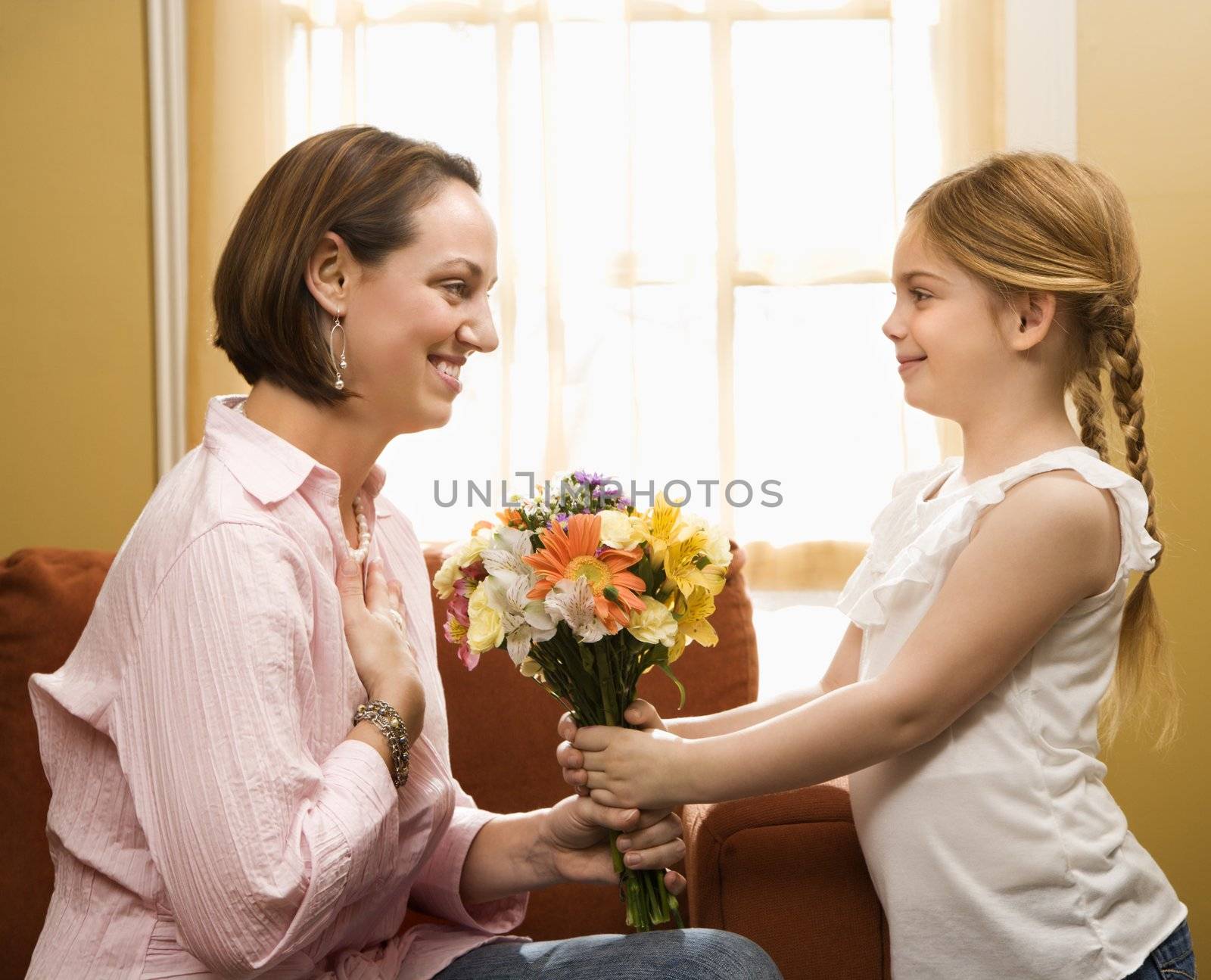 Caucasian girl giving mid adult mother a drawing.