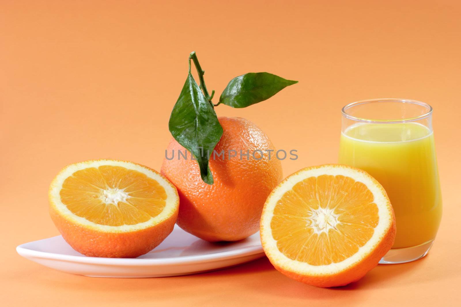 Orange Juice with Fruits on a plate on orange Background