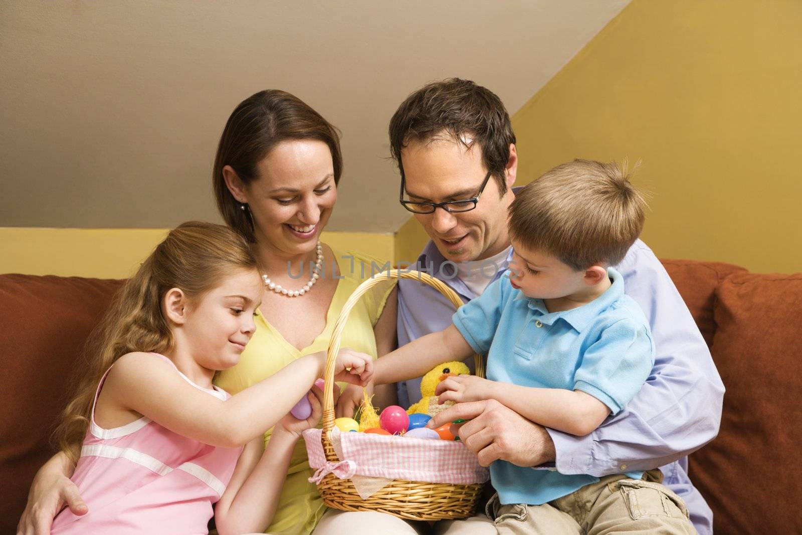 Caucasian family on couch looking at Easter basket.