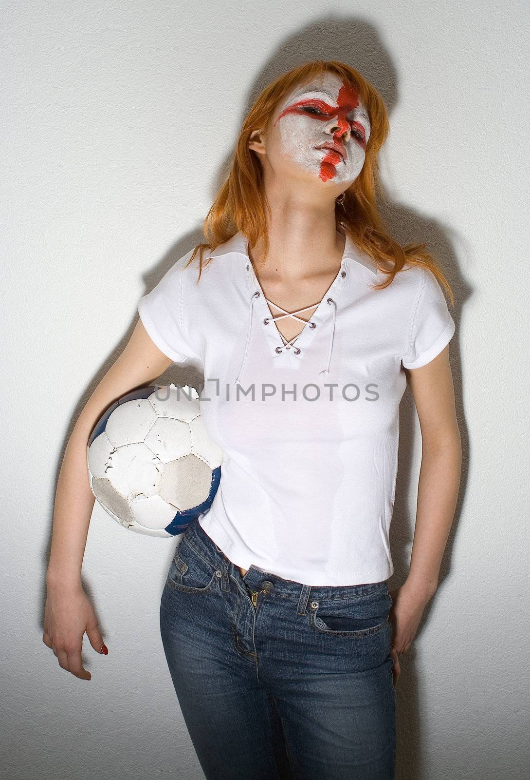 english football makeup girl standing in front of a wall, holding soccer ball