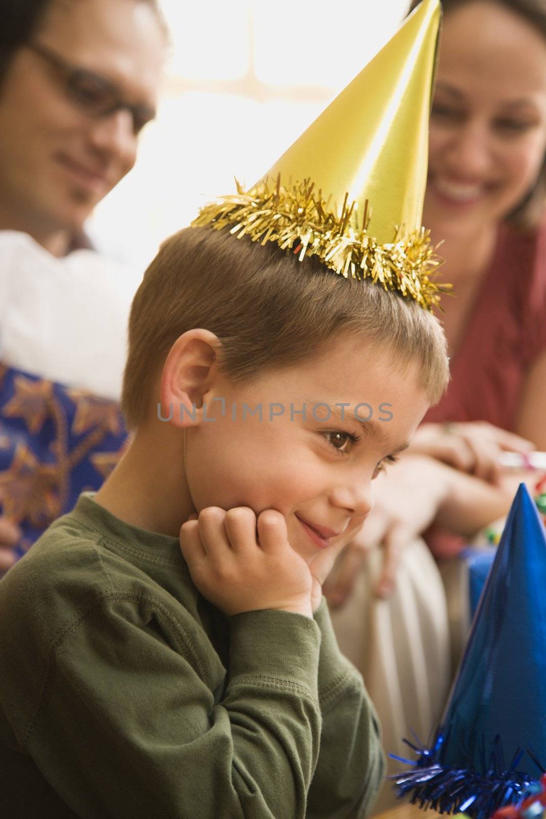 Caucasian boy at birthday party looking to the side and smiling.