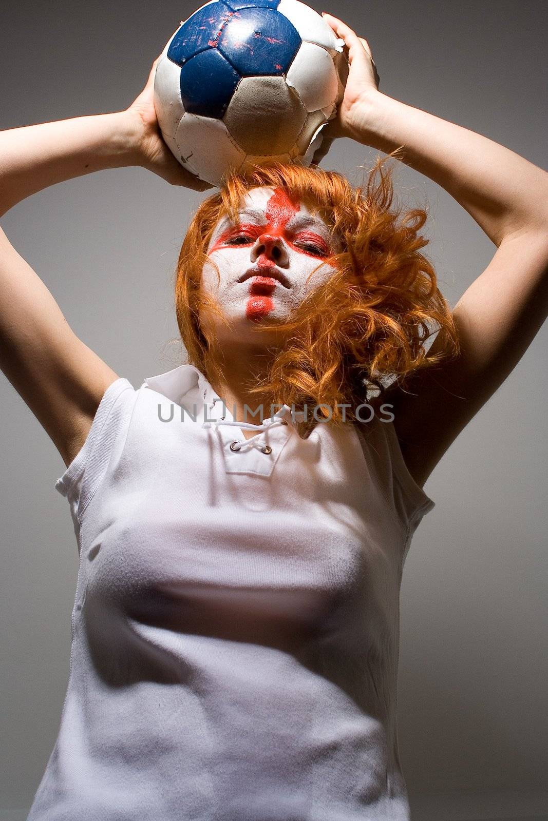 english football makeup girl holding worn soccer ball, looking down