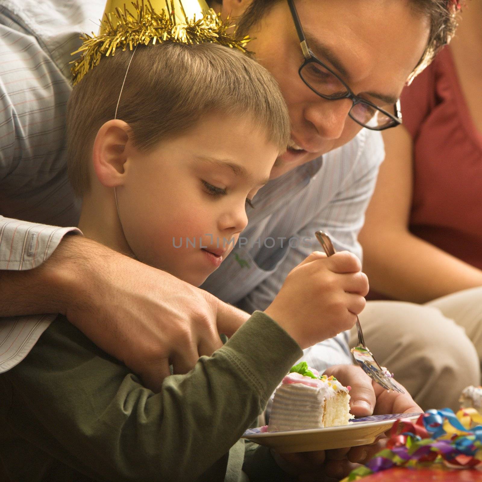Caucasian mid adult father helping son with birthday cake.