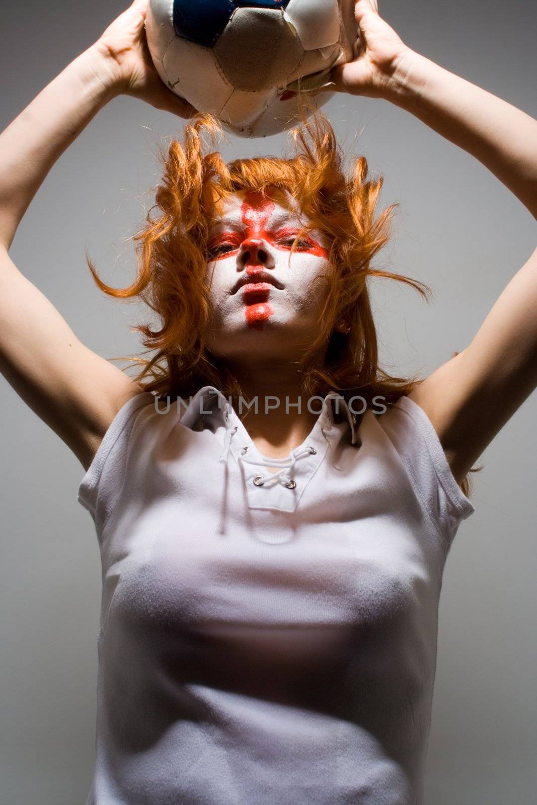 english football makeup girl holding worn soccer ball, looking proudly into camera