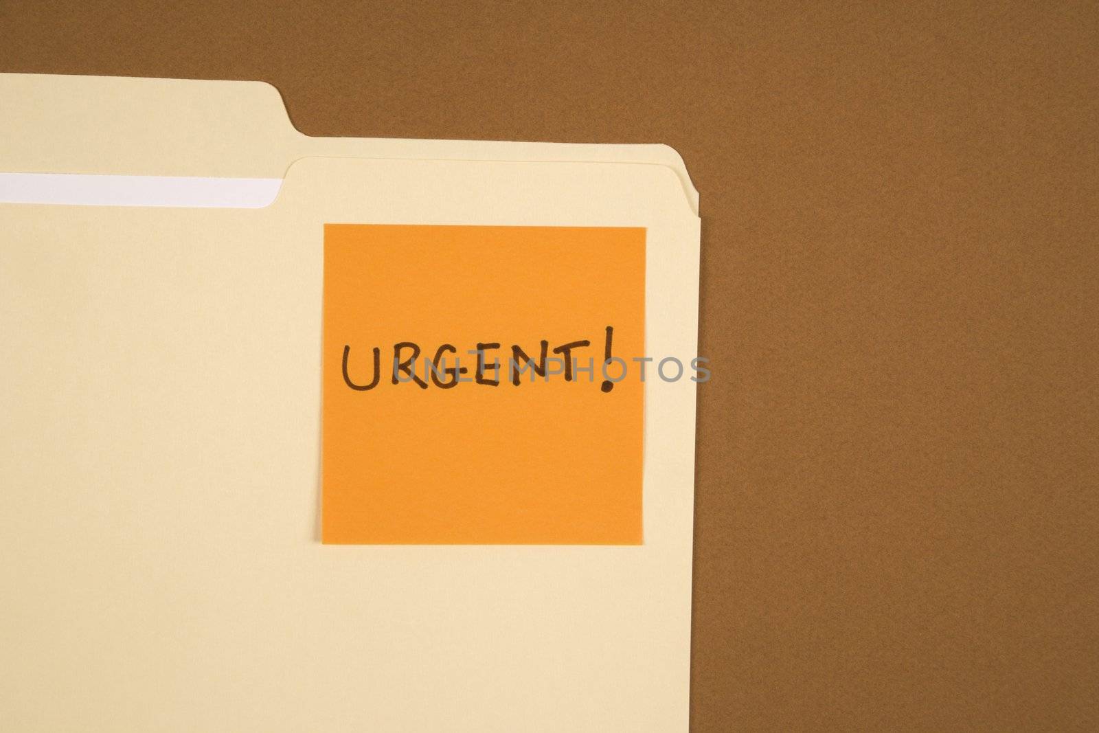 Folder with an orange sticky note attached reading urgent on brown background.