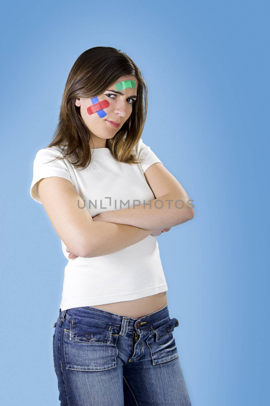 Beautiful woman with colored bandages on the face over a blue background