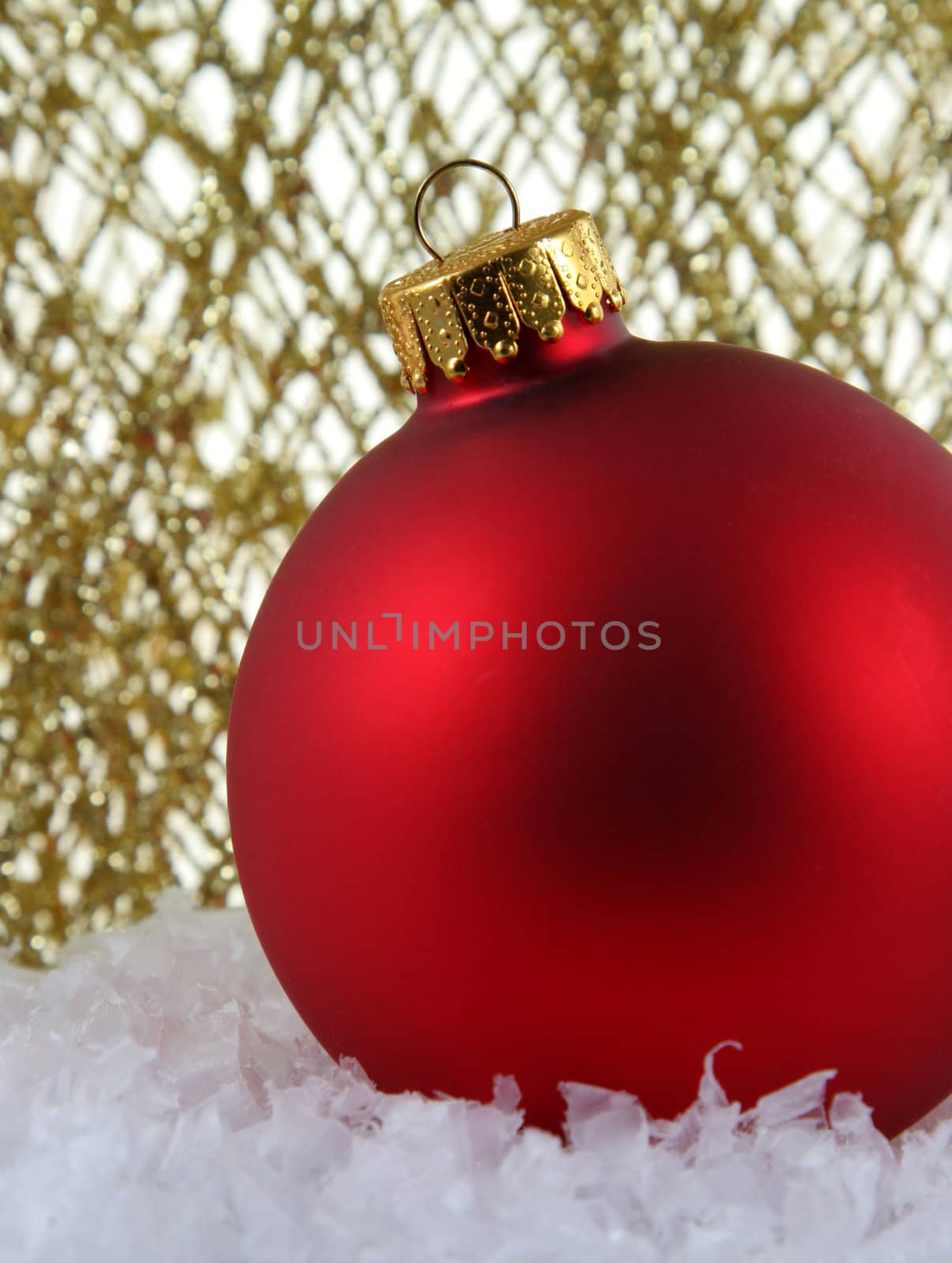 A red Christmas bauble backed by gold glittery strings.
