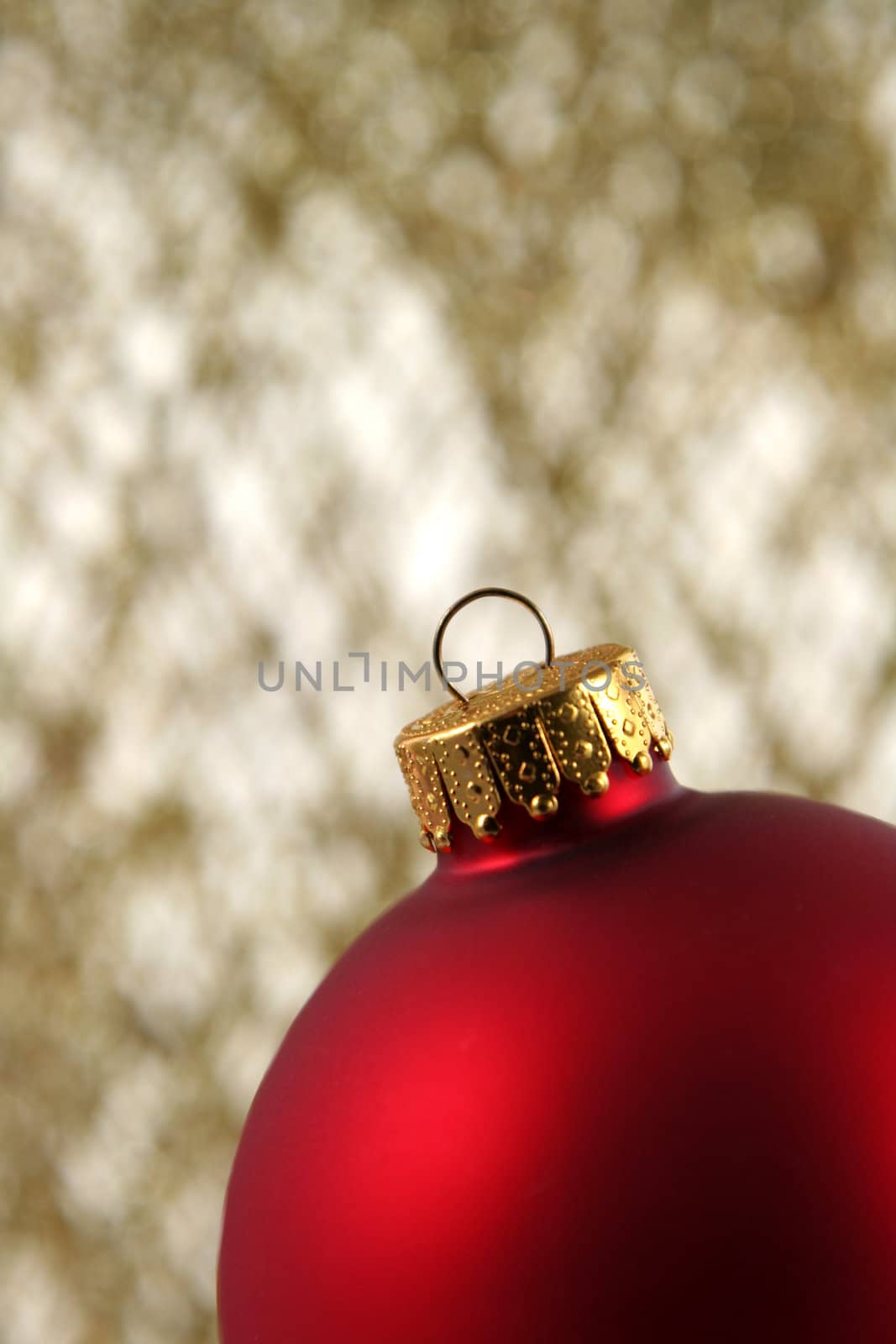 A red Christmas bauble backed by gold glittery strings.
