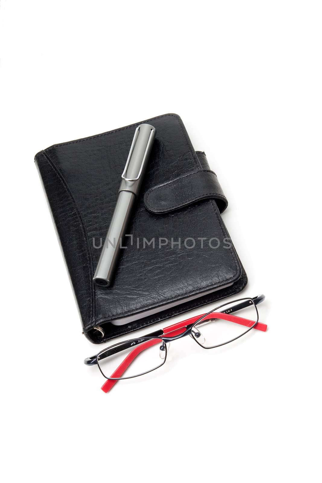 Closed Black Planner, with a silver pen on top, and a glasses on bottom. On white.