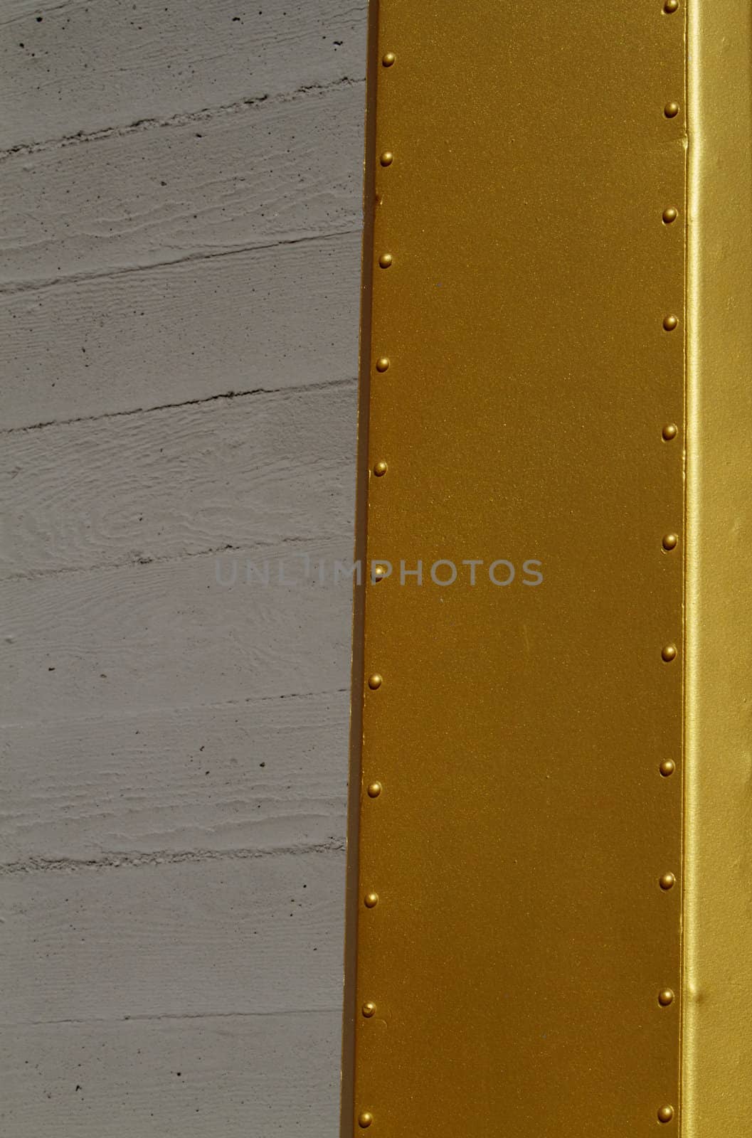 Abstract of small portion of gold beam next to concrete wall