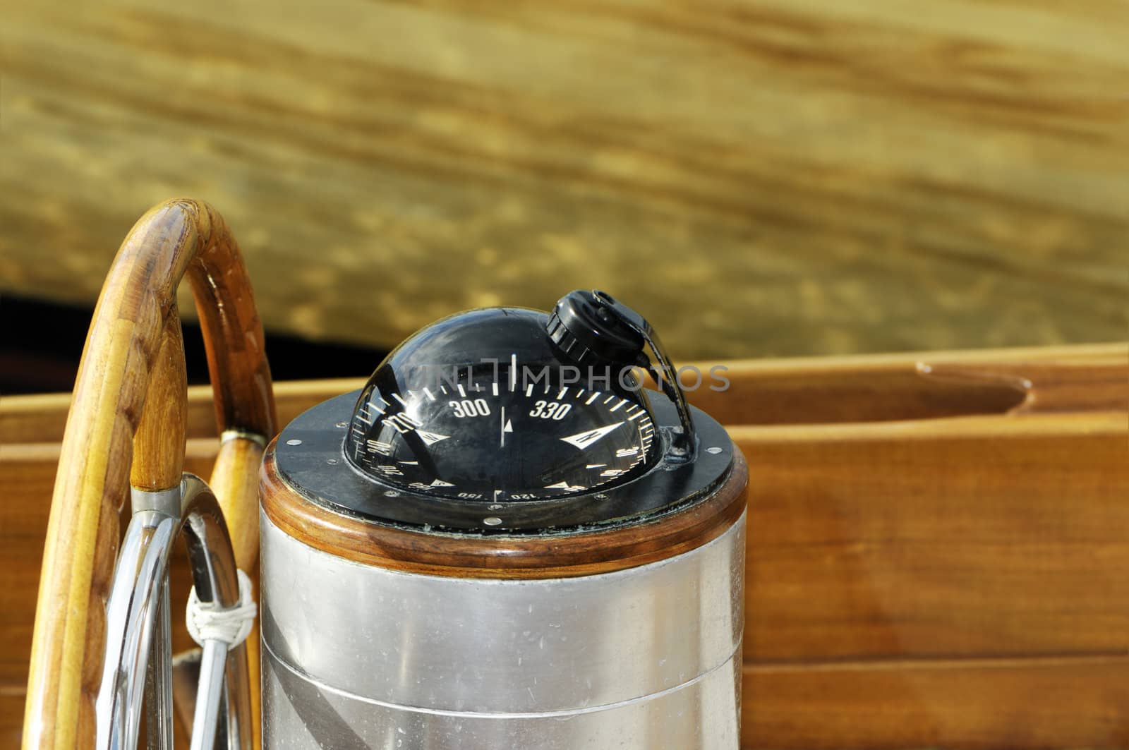 Detail of a steering wheel and a nautical compass on a wooden sailboat