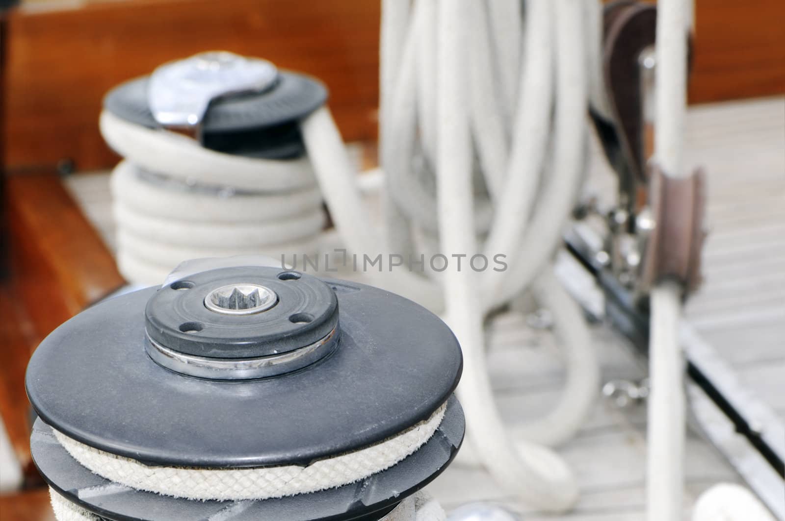 Detail of a winch with other equimpment of a sailboat in background