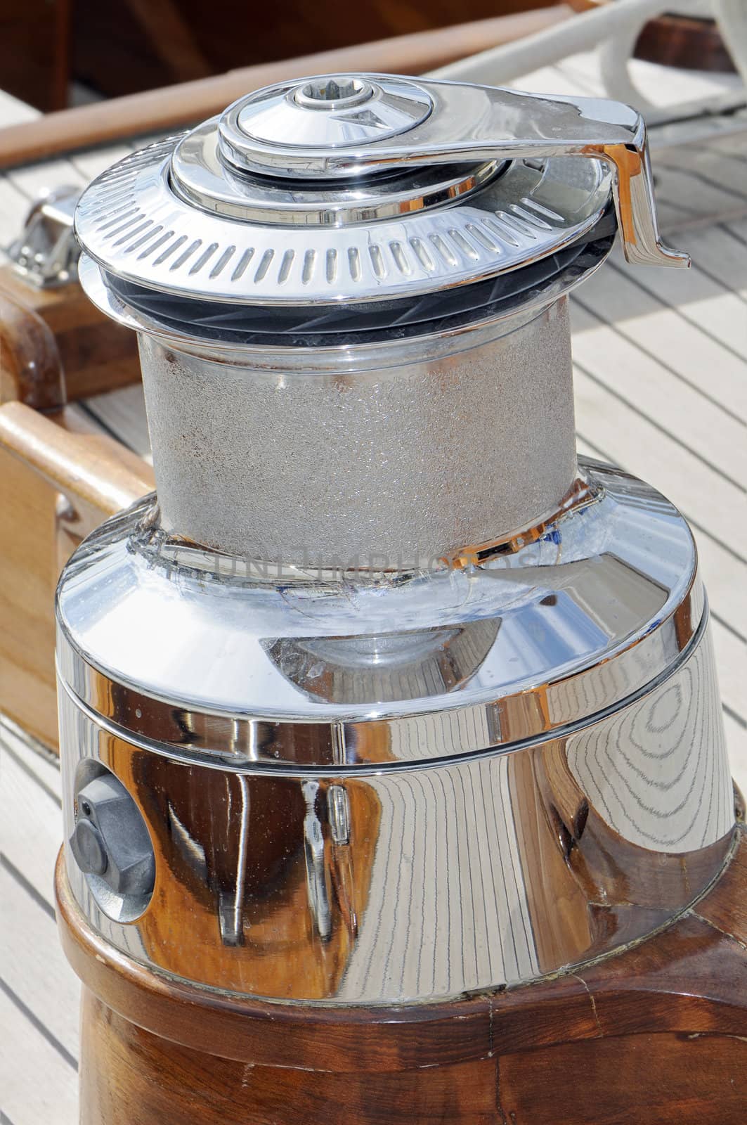 Close-up of a big cromed winch on a wooden sailboat