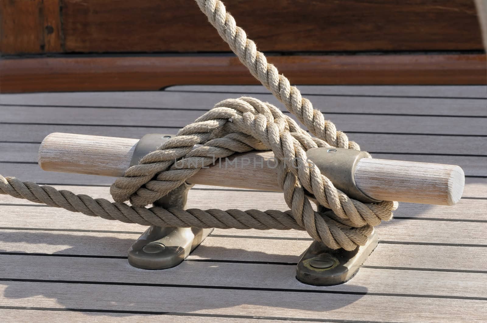 Detail of a rope tied-up on wooden bitt securing boat to dock