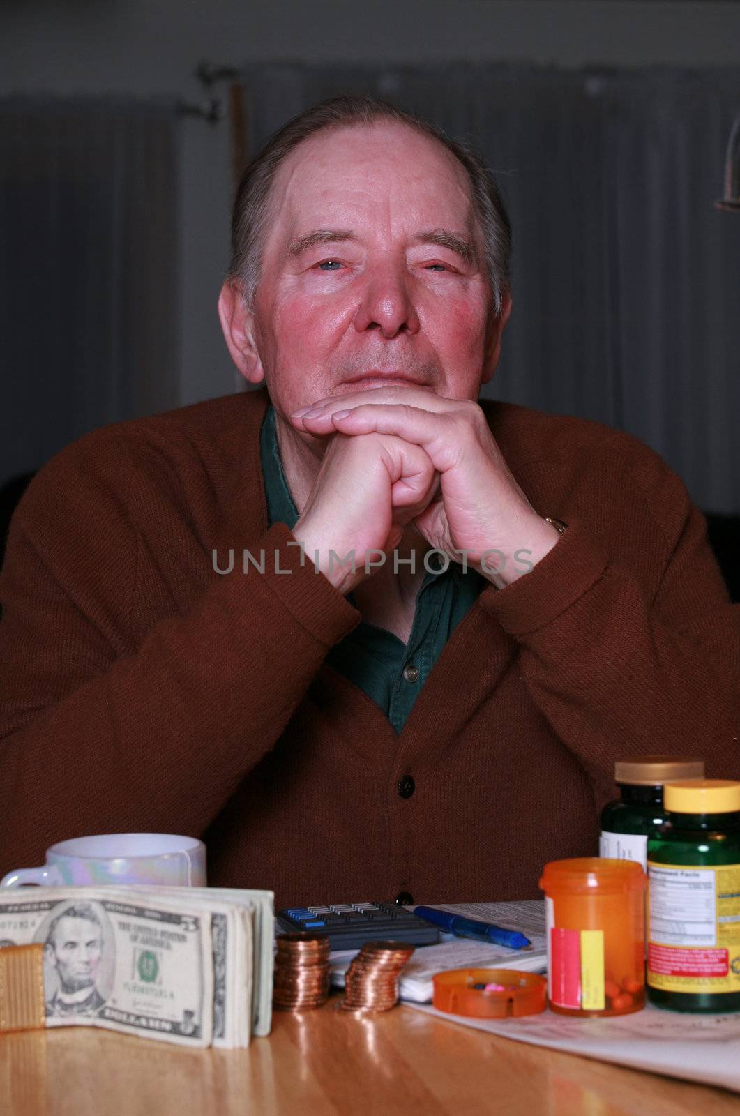 Elderly man with money and medications, looking into camera with serious expression