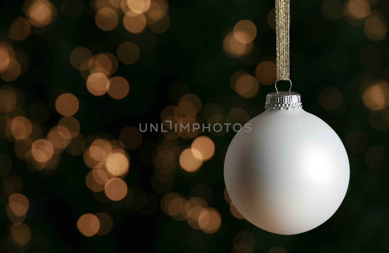 White Christmas ornament against lit Christmas tree background