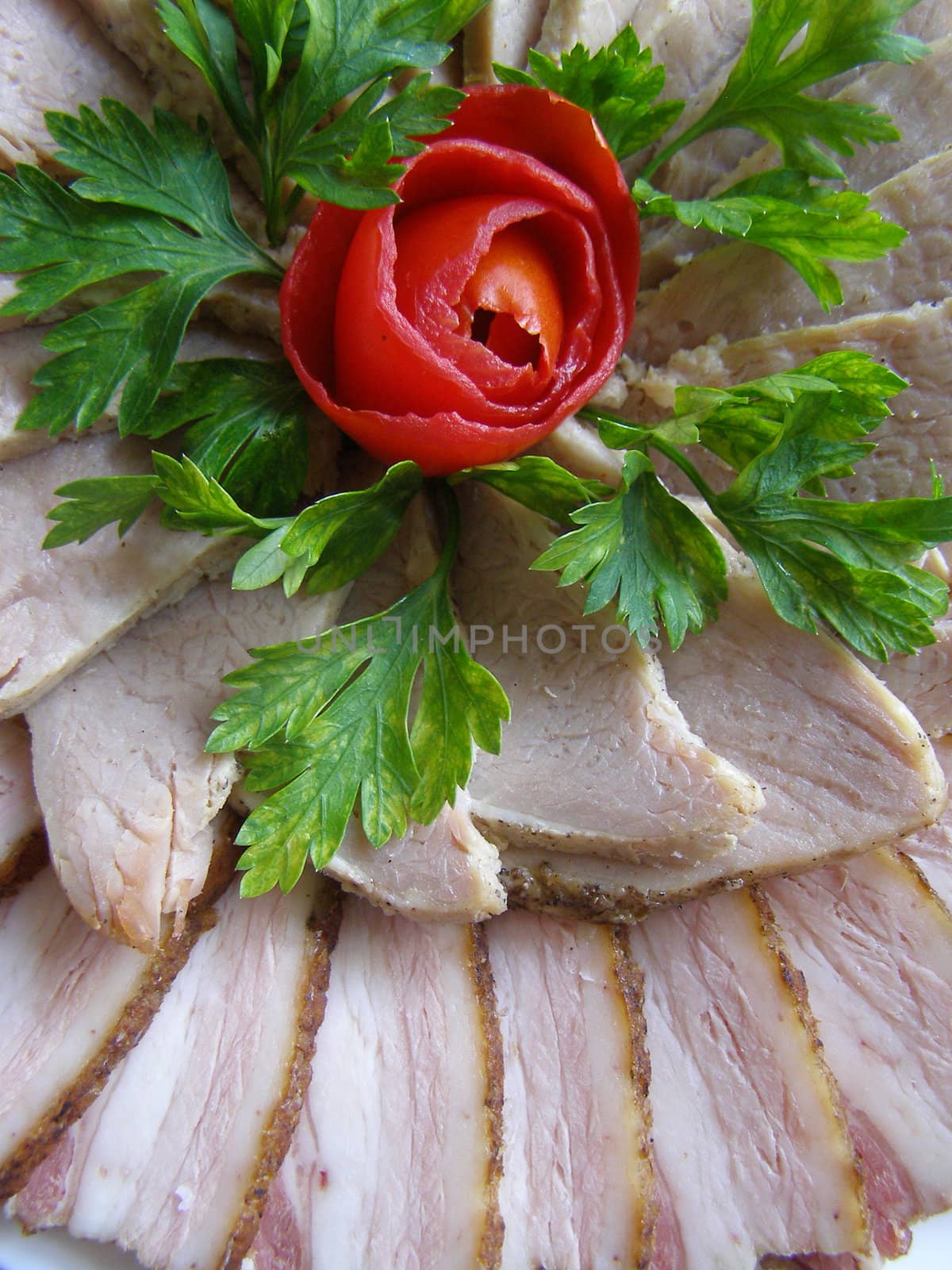 cold baked pork lay to the plate and decorated with parsley and tomato 