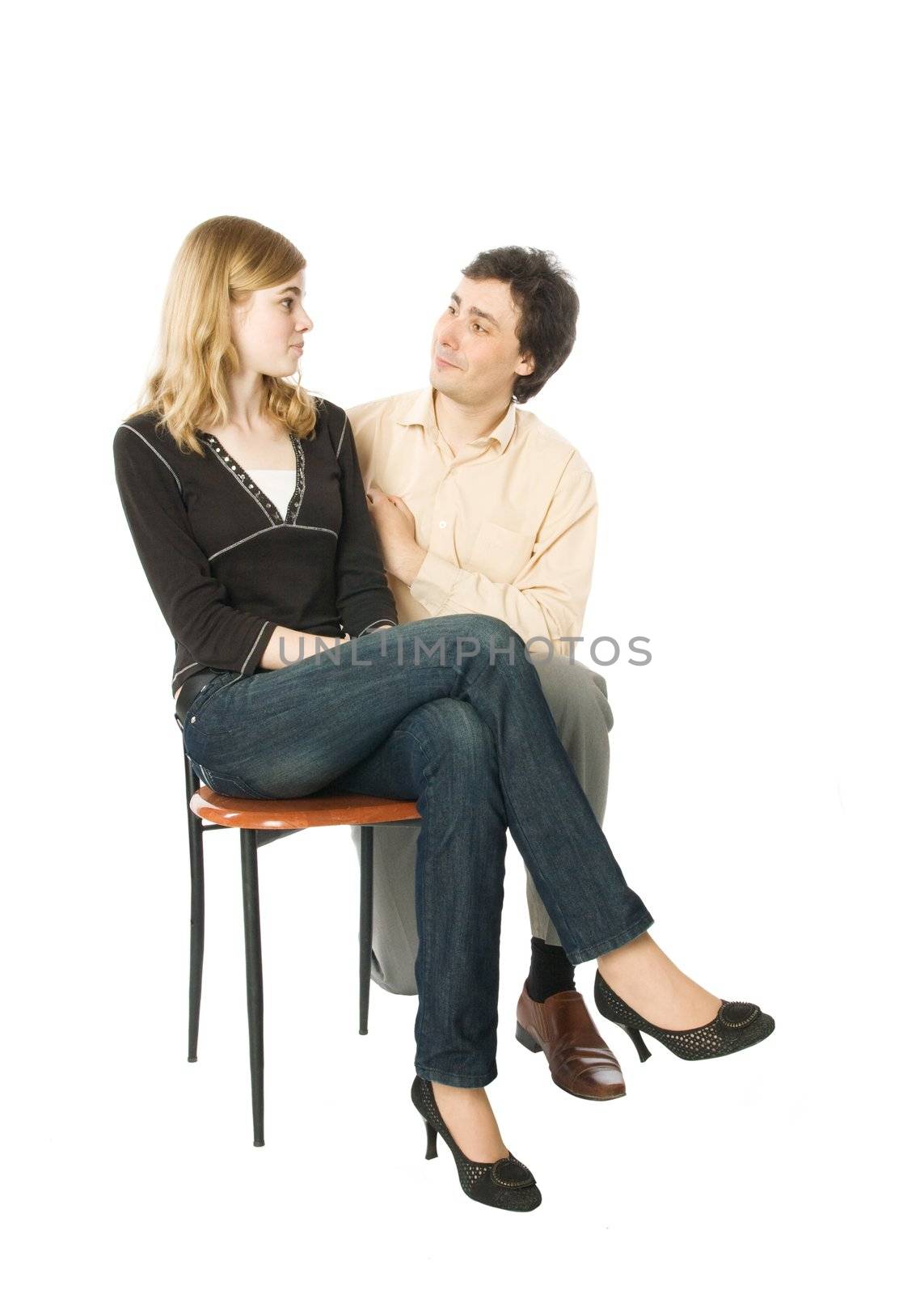 Young girl sitting on a chair and a man smiling to her