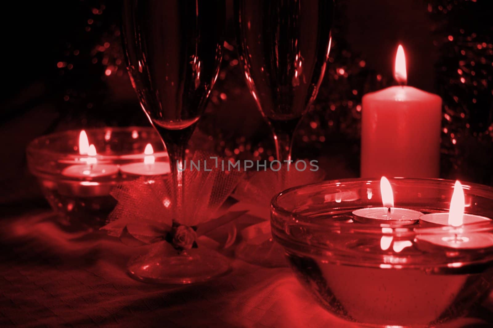 glasses of champagne, candles with christmas decorations, red toned