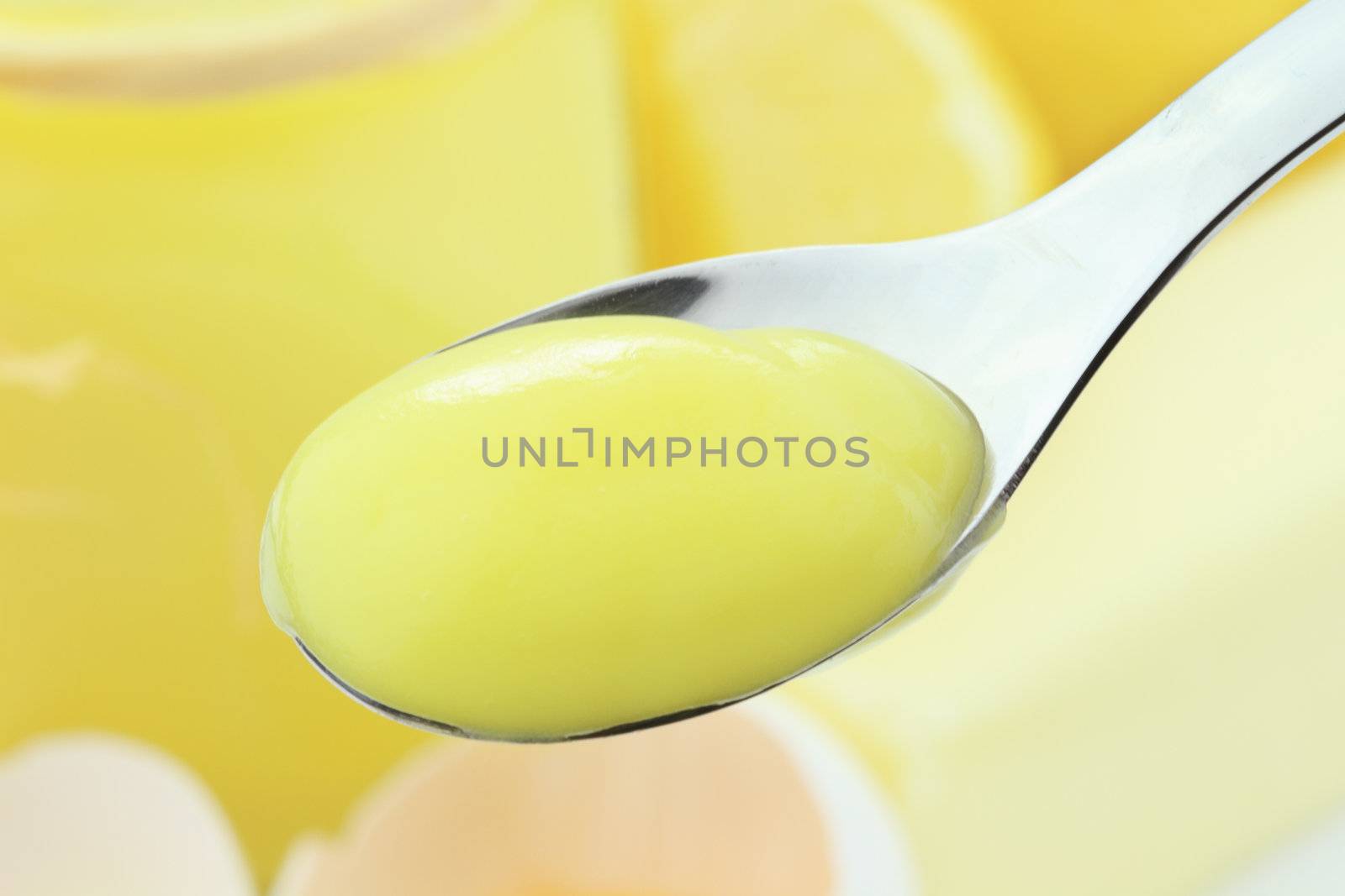 Spoonful of lemon curd or lemon pudding with ingredients in background. Extreme shallow dof with selective focus on spoonful of pudding.