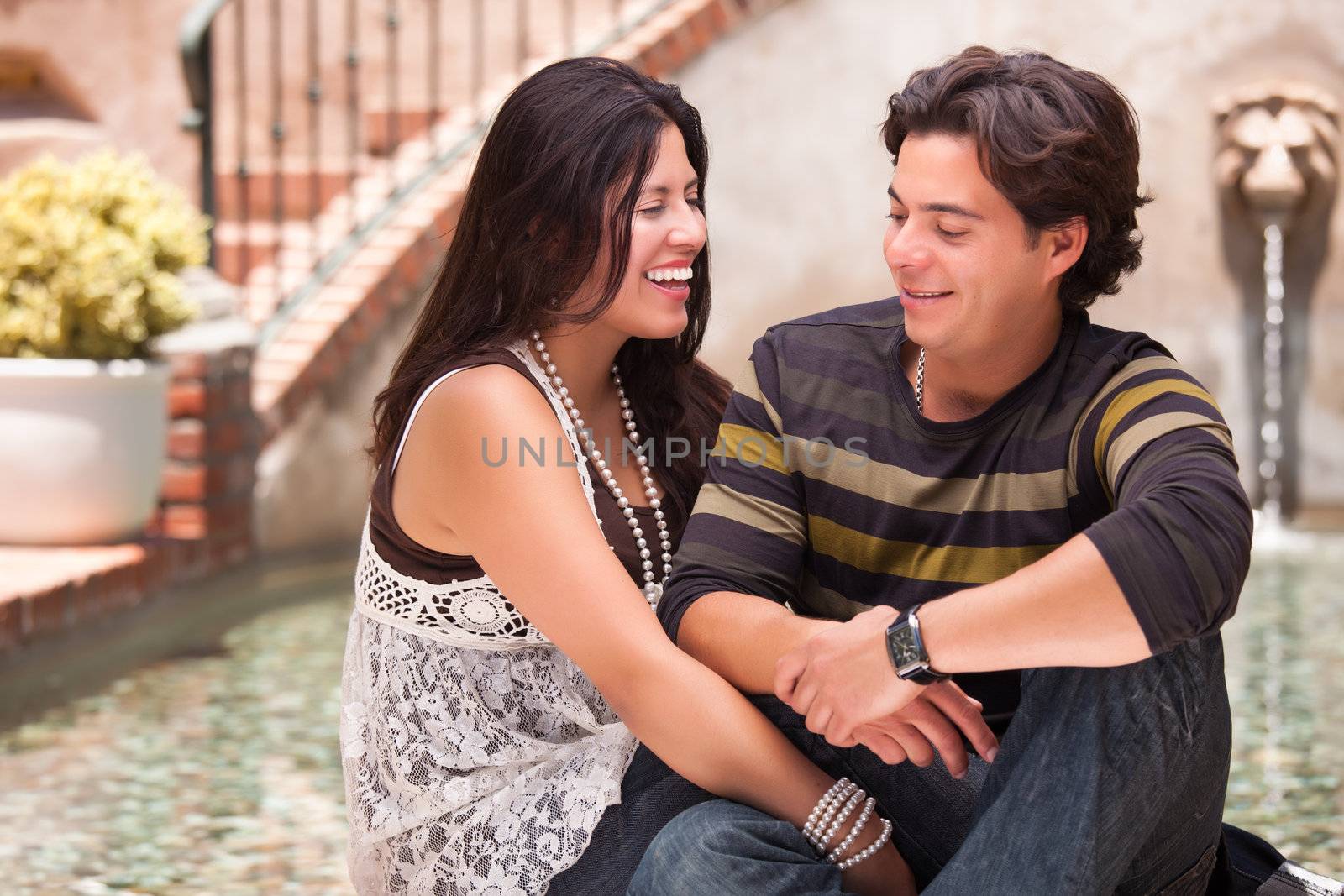 Attractive Hispanic Couple Ejoying Each Other At A Fountain.