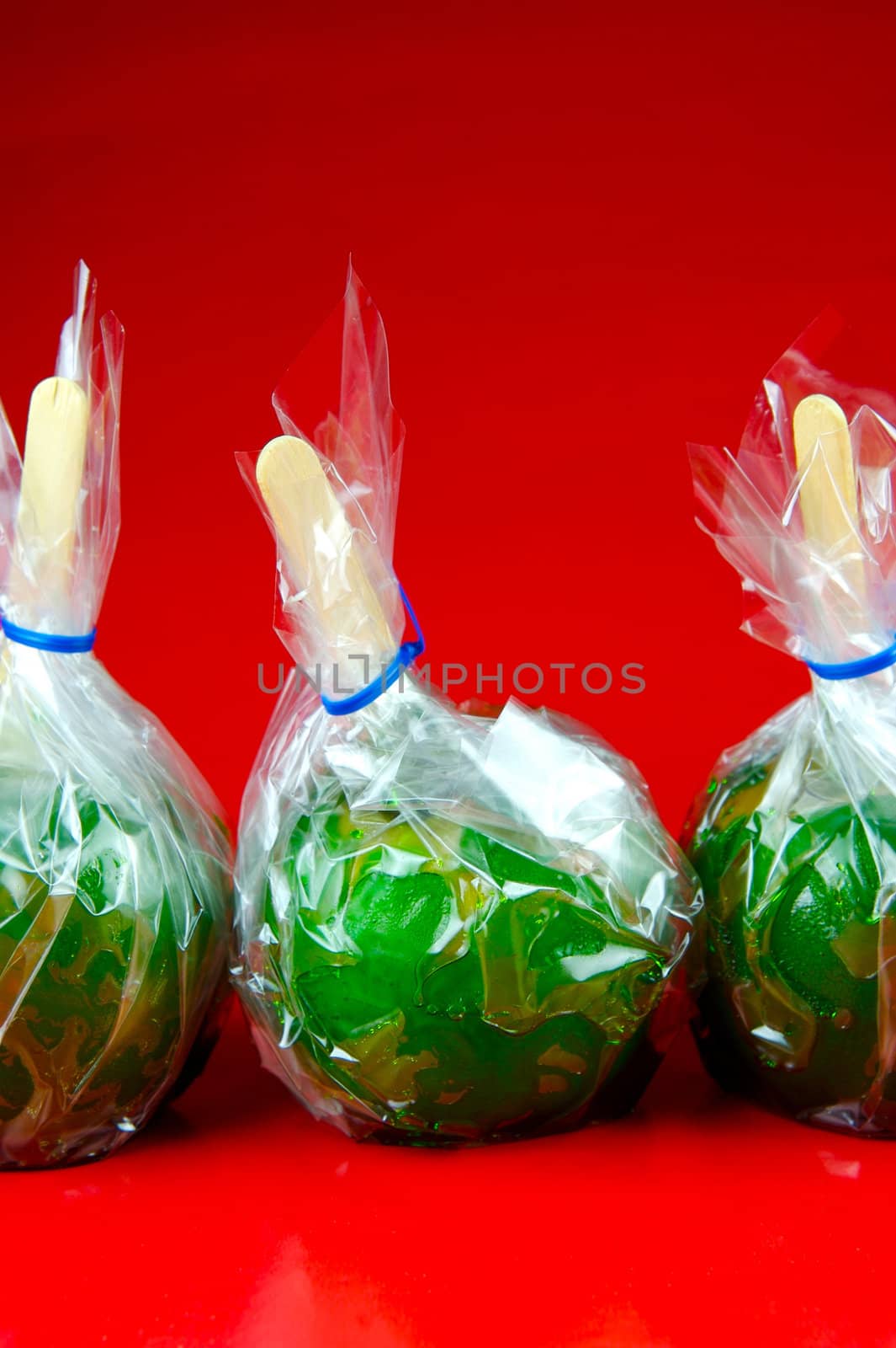 Green toffee apples isolated against a red background