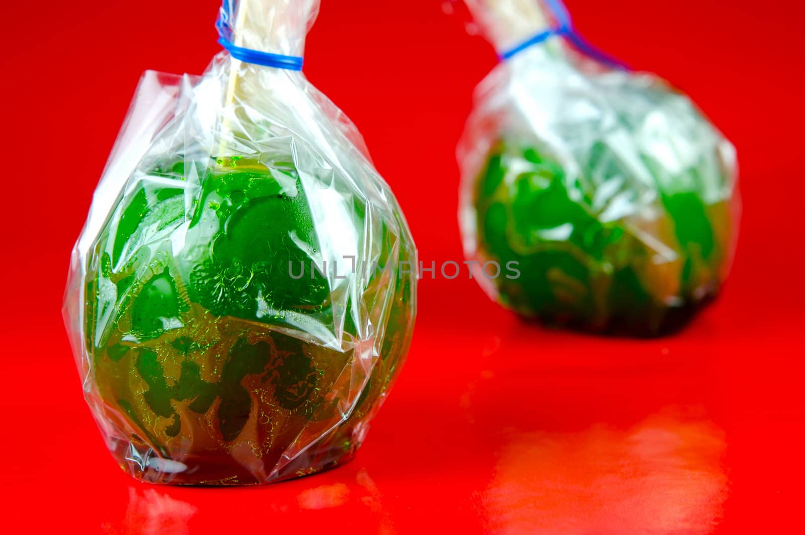 Green toffee apples isolated against a red background