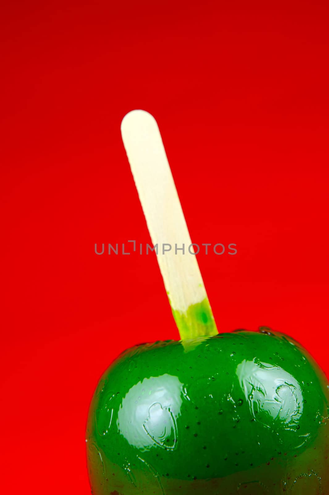 Green toffee apples isolated against a red background