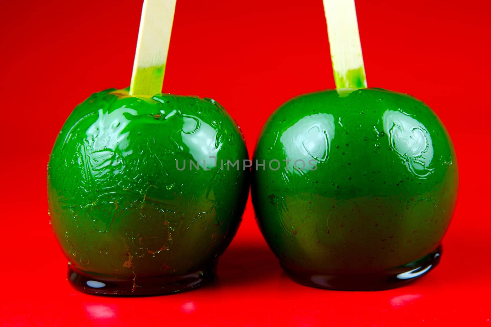 Green toffee apples isolated against a red background