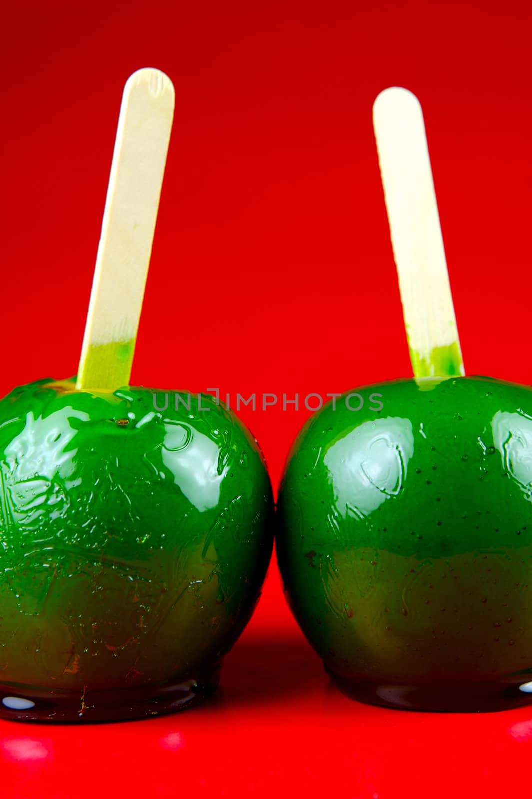 Green toffee apples isolated against a red background