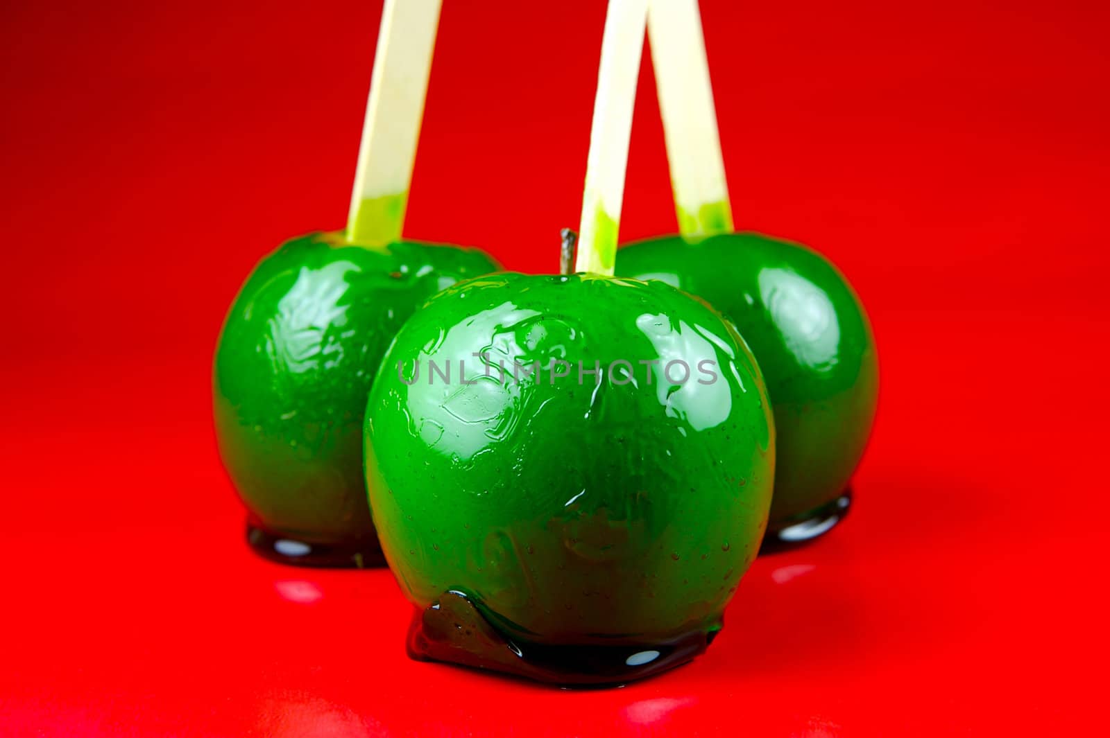 Green toffee apples isolated against a red background