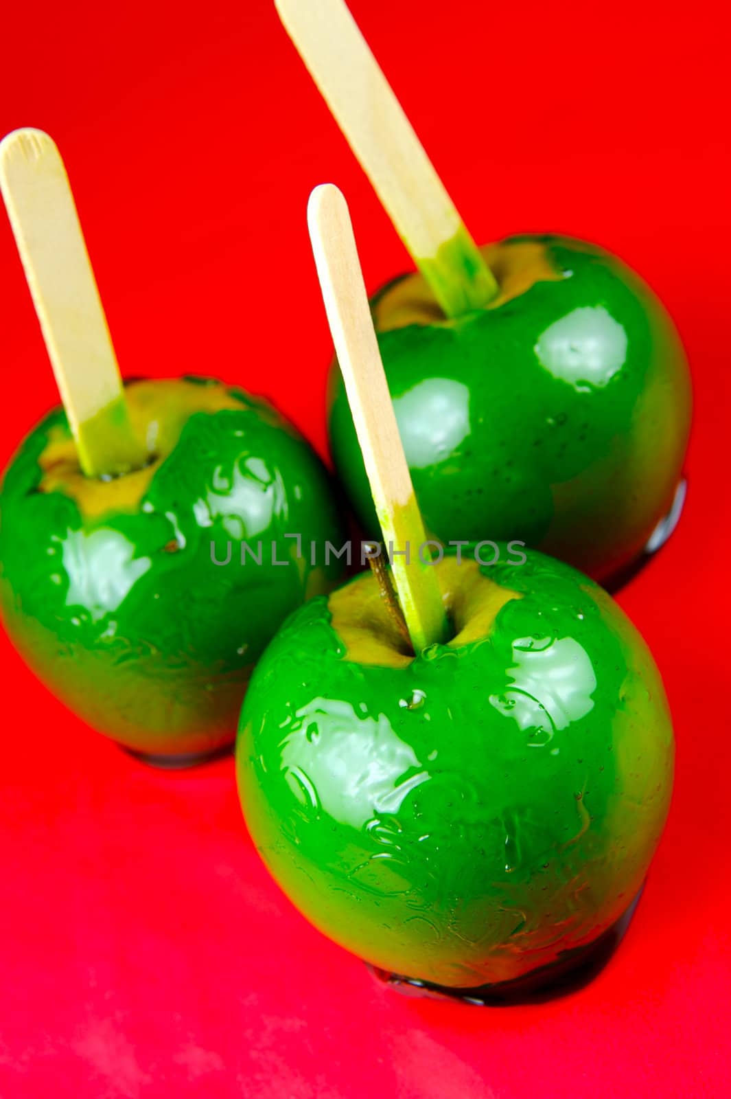 Green toffee apples isolated against a red background