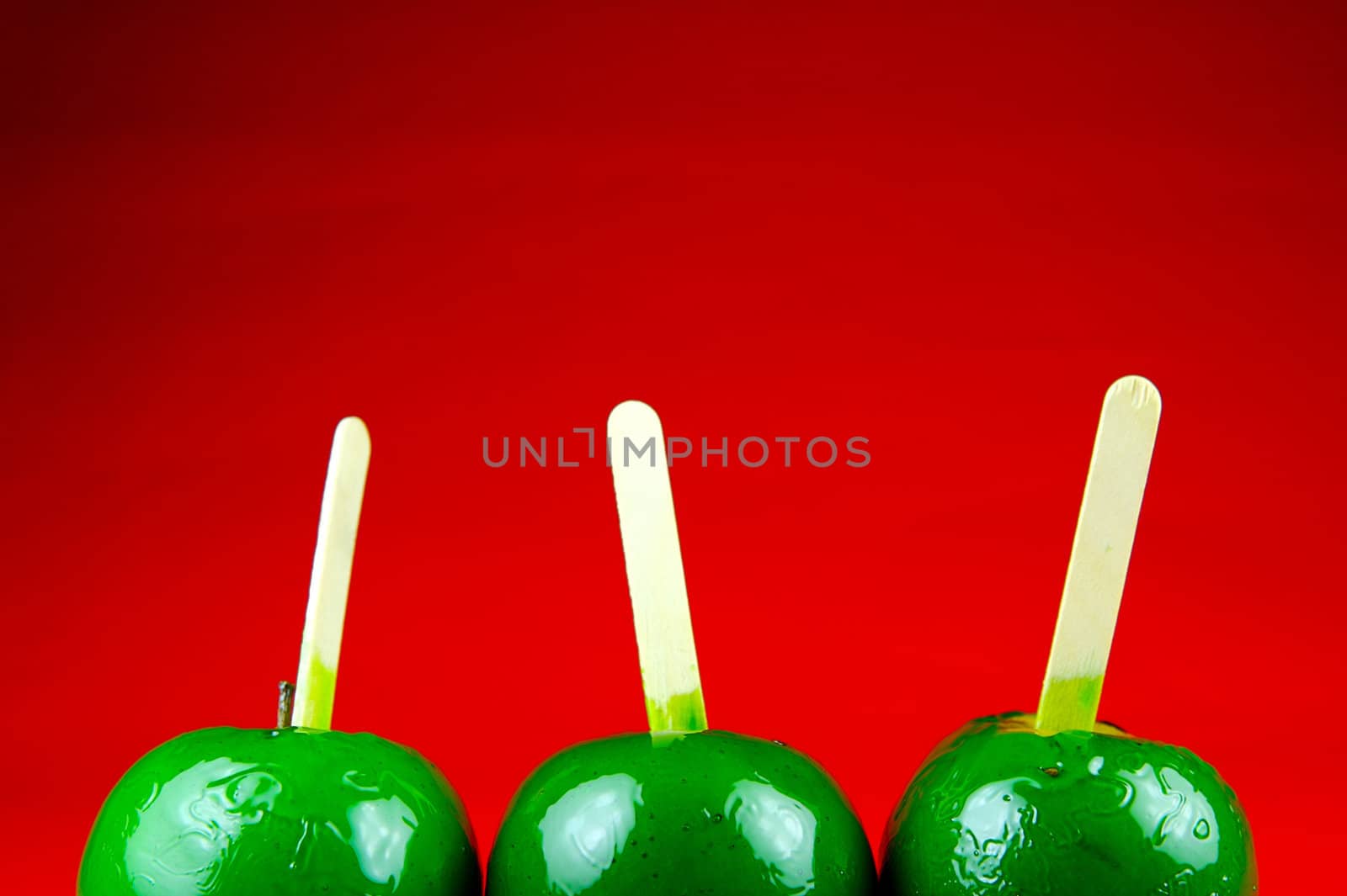 Green toffee apples isolated against a red background