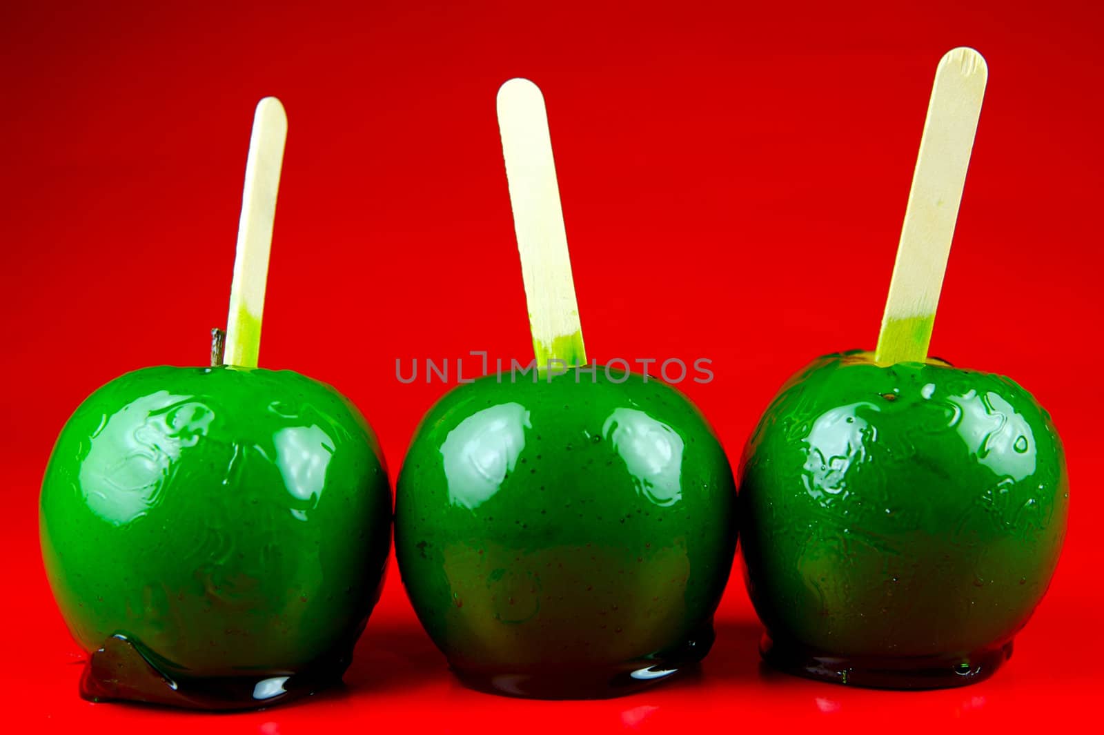 Green toffee apples isolated against a red background